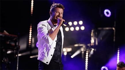 A singer at a church live concert performs on stage for an audience.