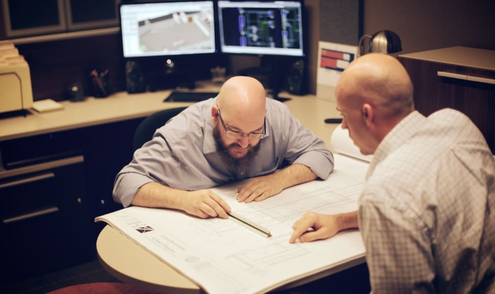 Two audio and visual engineers reviewing plans and layouts.